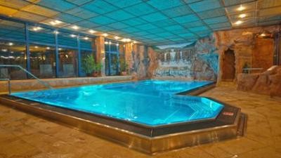 Beleuchtendes Hallenbad mit Felsenwand im Hintergrund